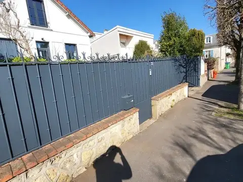 Clôture en fer gris anthracite avec brise-vue le long d'un trottoir
