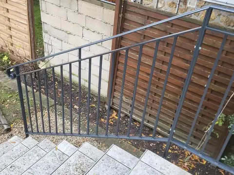 Main courante d'escalier en acier terminée par une crosse en volute