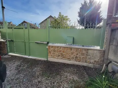 Portail battant et clôture brise-vue en acier vert sur muret en pierre